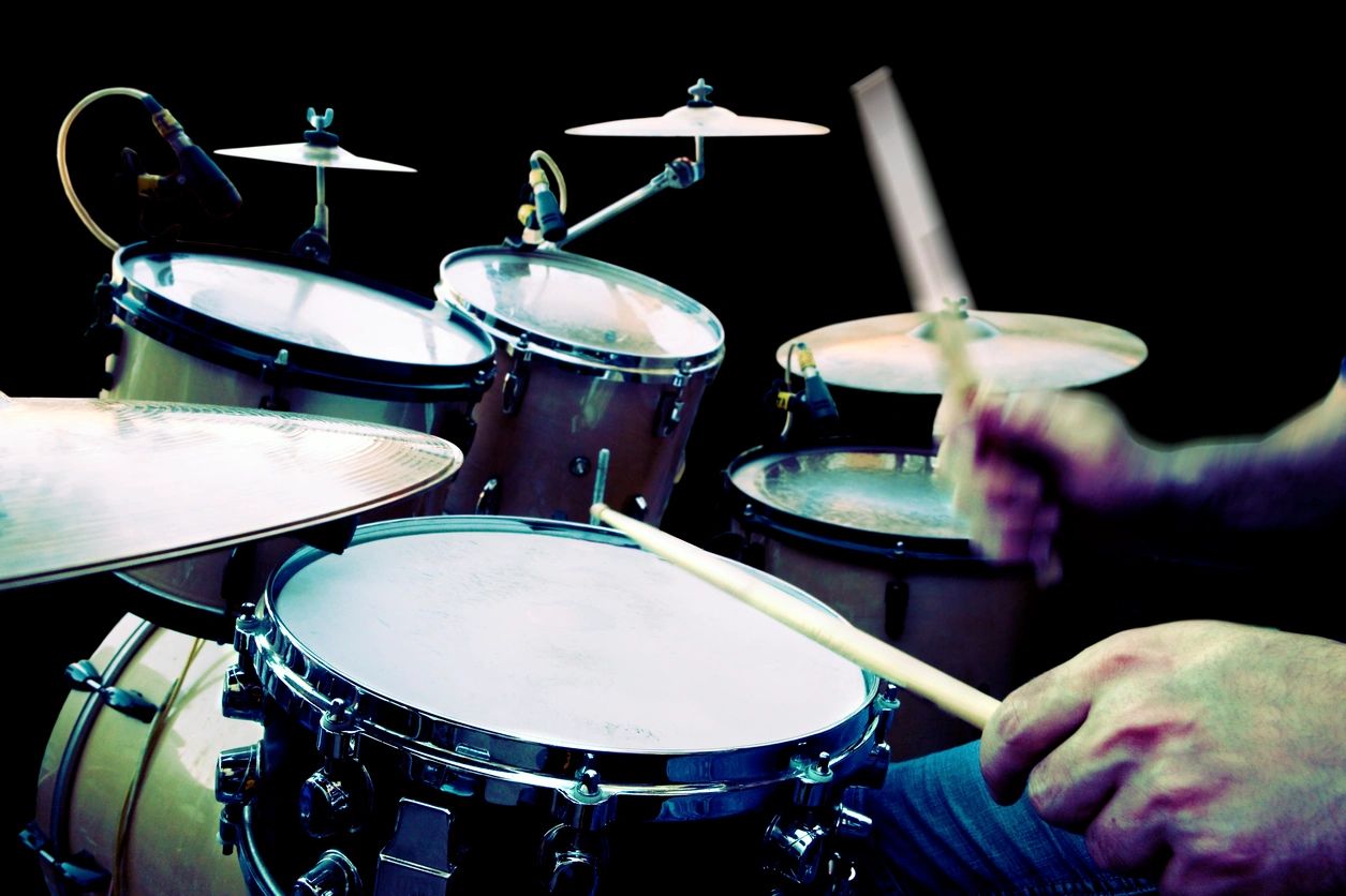 Young person playing on a drum kit.