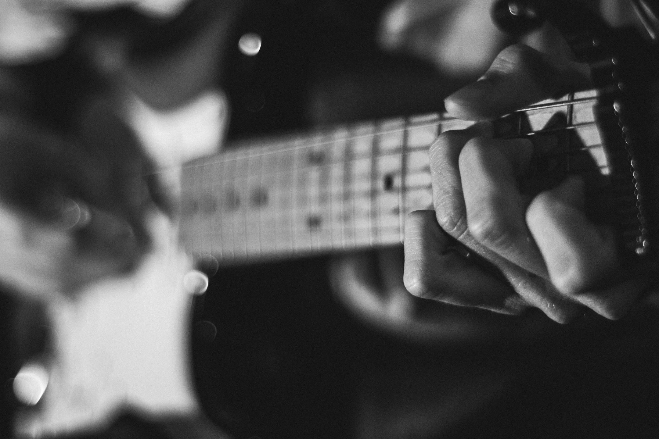 Young person playing guitar fret board.