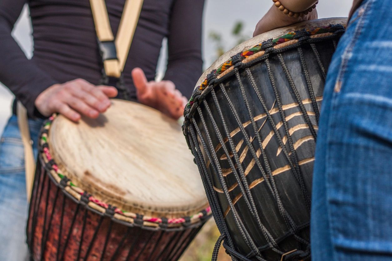 Young people playing bongos outdoors happily.