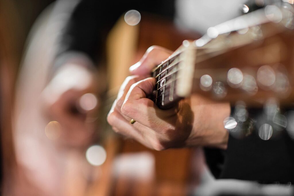 Hands on guitar fretboard about to play in sunny room